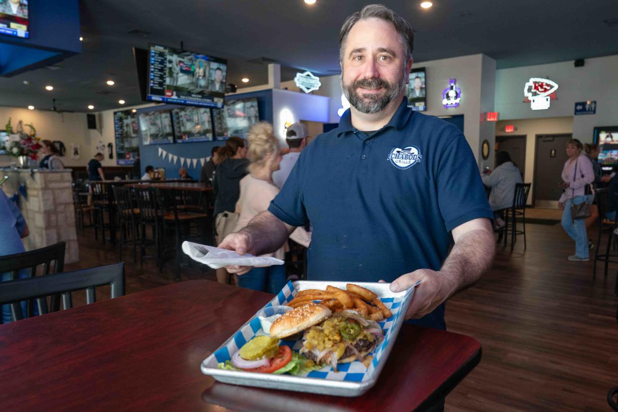 Ichabod's Grille general manager Danny Burnison brings out an order of the hulk smash burger with onion rings Wednesday during lunch hour. The newly renovated restaurant takes elements of Henry T's, while updating elements from the menu selection to interior seating and televisions.