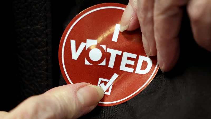 A voter applies her “I voted” sticker at the Salt Lake County Government Center in Salt Lake City on Wednesday, Nov. 21, 2023.