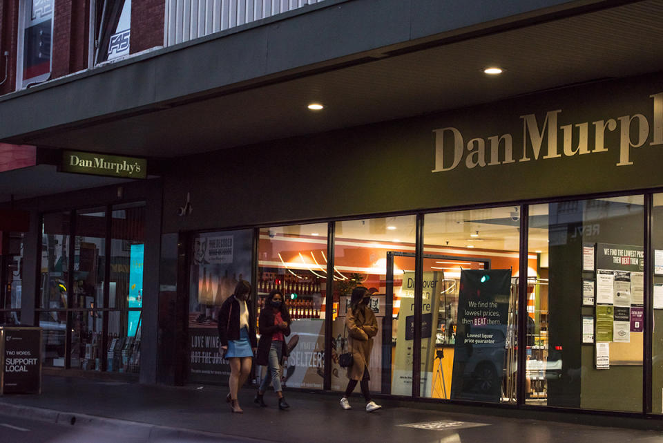 Three women walking past Dan Murphy's store