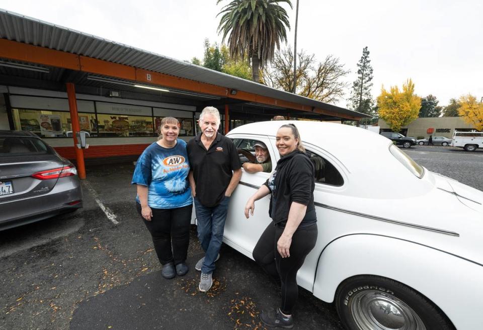 A&W owner Johnny Matthews and his manager, Jennifer Rushman, left, assistant manager Julie Hale, right, and loyal customer Jerry in his 1941 Chevy Master Deluxe coupe pose for a picture at A&W restaurant in Modesto, Calif., Friday Nov. 17, 2023. The “American Graffiti” era drive-in burger joint is closing after 66 years of continuous service.