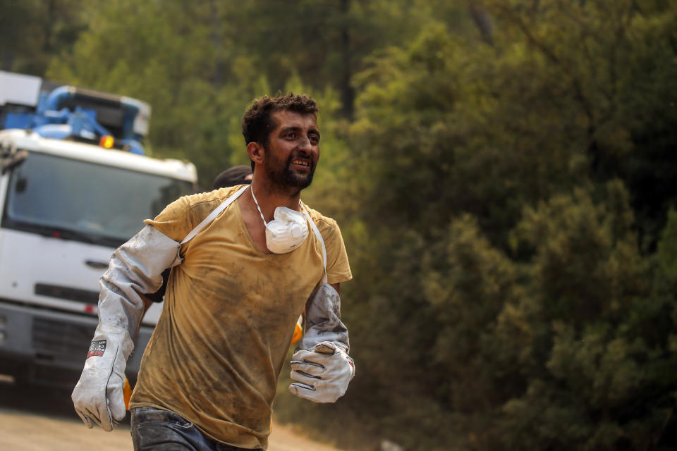 A Turkish volunteer runs as he heads to fight wildfires in Turgut village, near the tourist resort of Marmaris, Mugla, Turkey, Wednesday, Aug. 4, 2021. As Turkish fire crews pressed ahead Tuesday with their weeklong battle against blazes tearing through forests and villages on the country's southern coast, President Recep Tayyip Erdogan's government faced increased criticism over its apparent poor response and inadequate preparedness for large-scale wildfires.(AP Photo/Emre Tazegul)