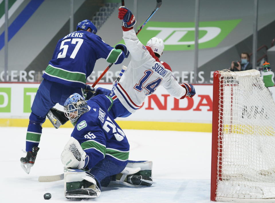 Vancouver Canucks defenseman Tyler Myers (57) clears Montreal Canadiens centre Nick Suzuki (14) away from Canucks goaltender Thatcher Demko (35) during the first period of an NHL hockey game Thursday, Jan. 21, 2021, in Vancouver, British Columbia. (Jonathan Hayward/The Canadian Press via AP)