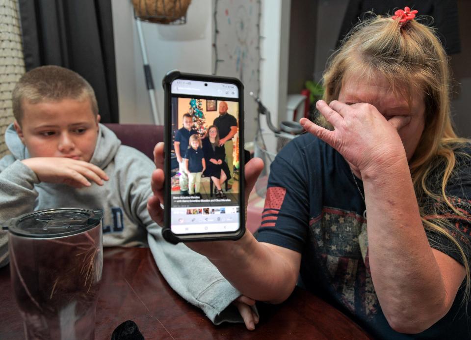 Darra Ann Morales, right, shows a photo of her son Chaz and his family on her phone as Chaz Jr. comforts his grandmother at their home in Slidell, La., on April 14.