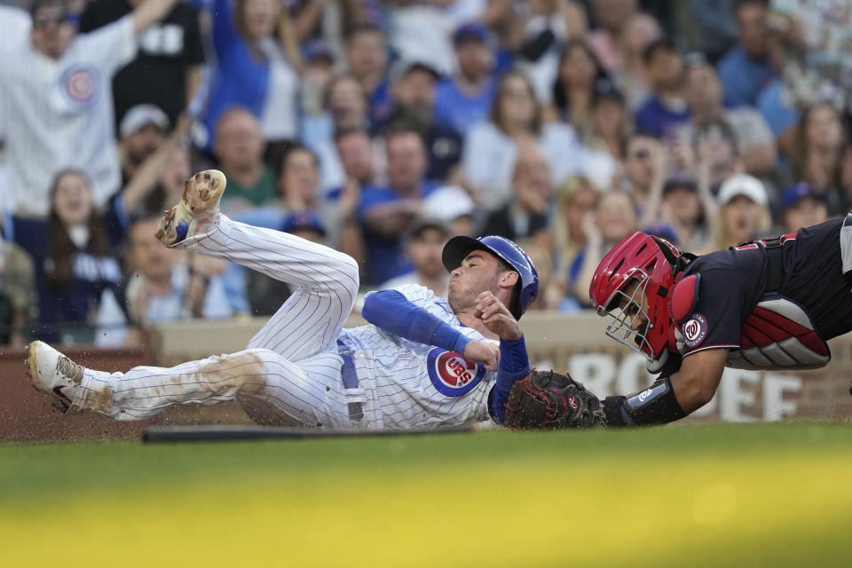 Chicago Cubs' Cody Bellinger, left, scores past Washington Nationals catcher Keibert Ruiz, off Christopher Morel's single during the second inning of a baseball game Monday, July 17, 2023, in Chicago. (AP Photo/Charles Rex Arbogast)