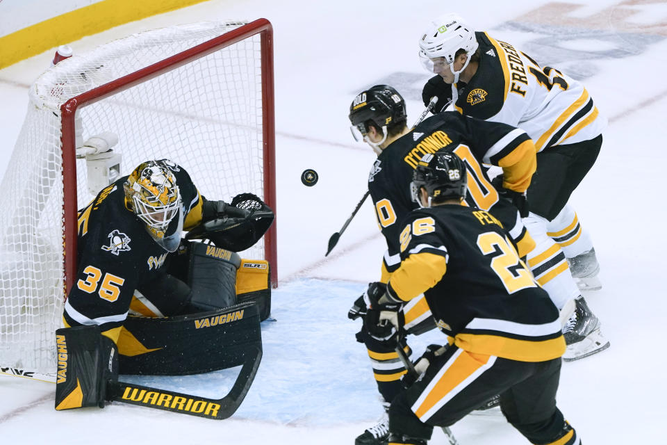 Boston Bruins' Trent Frederic, right, tries to bat the puck past Pittsburgh Penguins goaltender Tristan Jarry (35) during the first period of an NHL hockey game Tuesday, Nov. 1, 2022, in Pittsburgh. (AP Photo/Keith Srakocic)