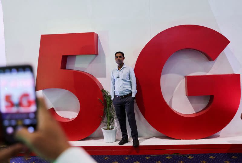 FILE PHOTO: A man takes a picture of a friend in front of a sign showing installation of the 5G network