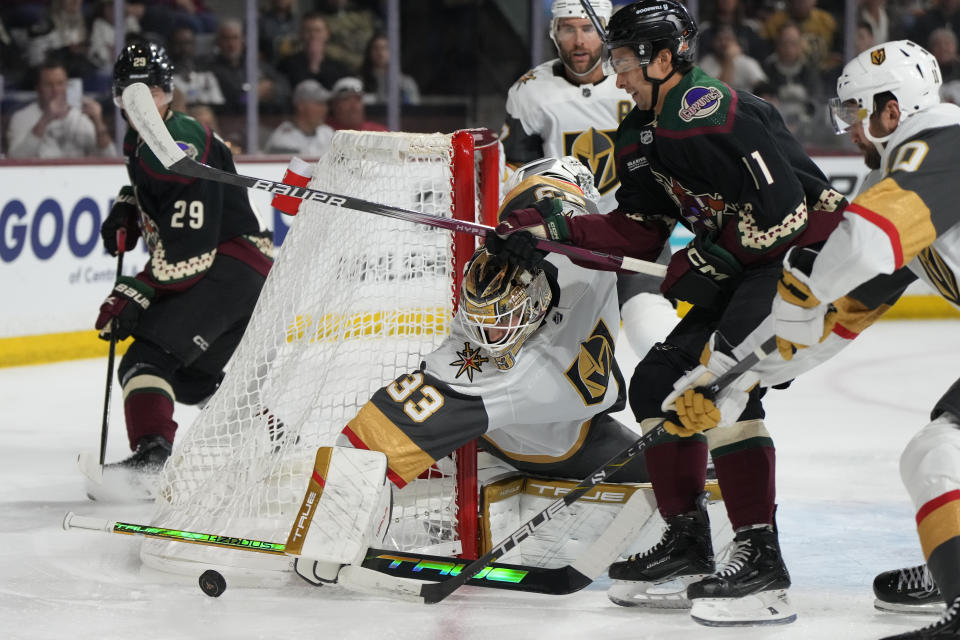 Vegas Golden Knights goaltender Adin Hill (33) makes a save on Arizona Coyotes right wing Dylan Guenther (11) during the first period of an NHL hockey game Thursday, Feb. 8, 2024, in Tempe, Ariz. (AP Photo/Rick Scuteri)