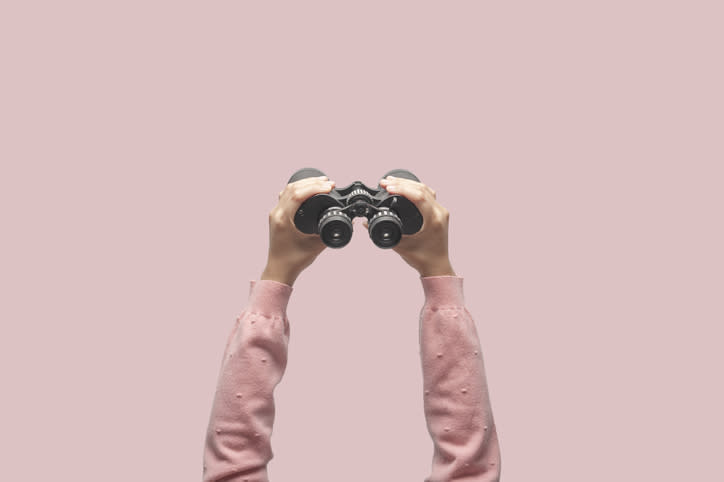 A pair of hands holding up a pair of binoculars.