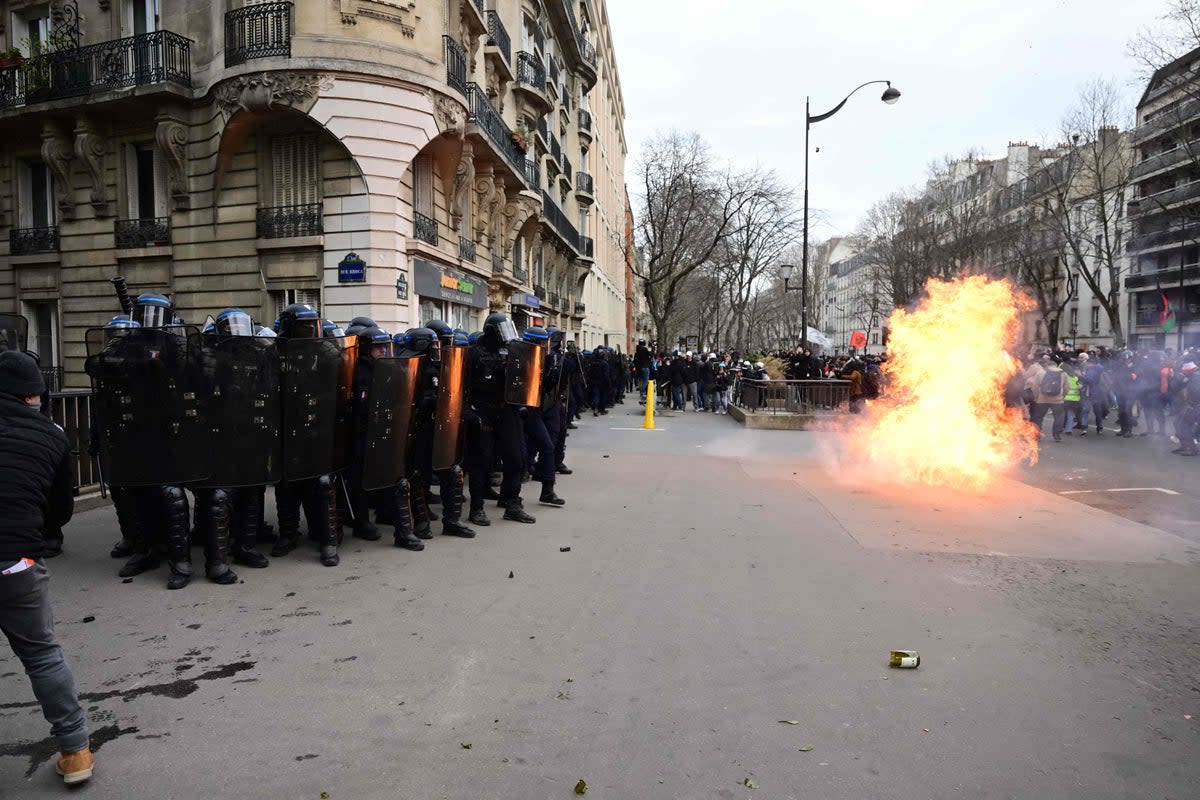 Police stand in formation as a petrol bomb explodes during clashes on the sidelines of a demonstration (AFP via Getty Images)