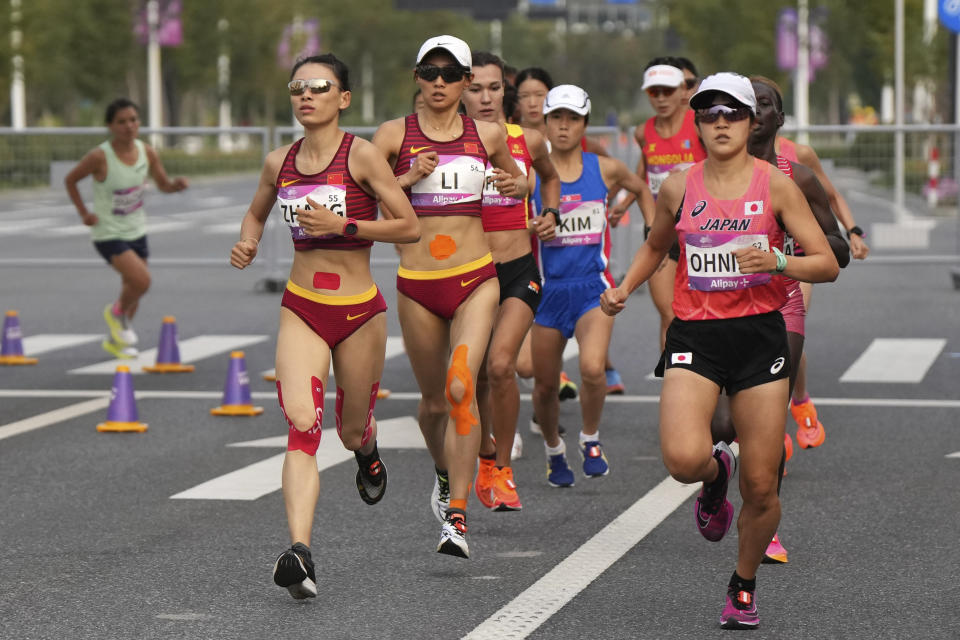 Silver medalist China's Zhang Deshun, left, competes with other runners during the women's marathon at the 19th Asian Games in Hangzhou, China, Thursday, Oct. 5, 2023. (Li Yibo/Pool Photo via AP)