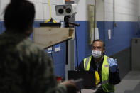 A Ford employee, left, has his temperature checked as he enters the Ford Rawsonville plant, Wednesday, May 13, 2020 in Ypsilanti Township, Mich. The plant was converted into a ventilator factory, as hospitals battling the coronavirus report shortages of the life-saving devices. The company has promised to deliver 50,000 by July 4. Ford and other automakers are preparing for the reopening of their plants next week. Factories must adopt measures to protect their workers, including daily entry screening and, once they are available, the use of no-touch thermometers. Those measures already are in effect at Rawsonville. (AP Photo/Carlos Osorio)