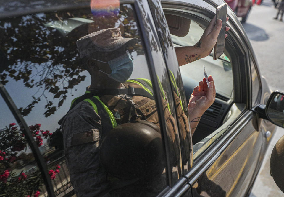 Un pasajero muestra su permiso de movilidad a un soldado en Santiago, Chile, el jueves 25 de marzo de 2021. Las autoridades anunciaron el restablecimiento de una cuarentena en toda la ciudad para ayudar a contener la propagación del COVID-19. (AP Foto/Esteban Felix)