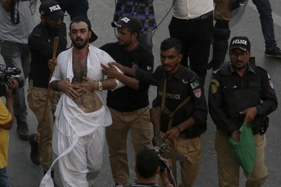 Police officers detain a supporter of former Pakistani Prime Minister Imran Khan's party, 'Pakistan Tehreek-e-Insaf' during a protest to condemn a shooting incident on their leader's convoy, in Karachi, Pakistan, Friday, Nov. 4, 2022. Khan who narrowly escaped an assassination attempt on his life the previous day when a gunman fired multiple shots and wounded him in the leg during a protest rally is listed in stable condition after undergoing surgery at a hospital, a senior leader from his party said Friday. (AP Photo/Fareed Khan)