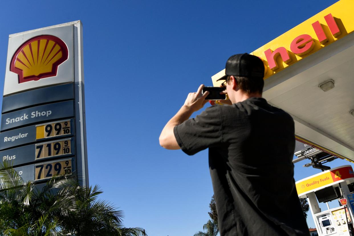 A person takes photographs of gas prices above $6.00 and $7.00 a gallon at a Shell gas station in Los Angeles on March 8, 2022. (Photo by Patrick T. FALLON / AFP)