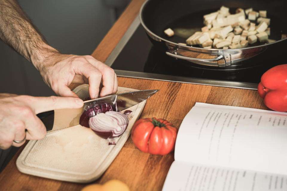 young man cooks a vegan dish from a cookbook