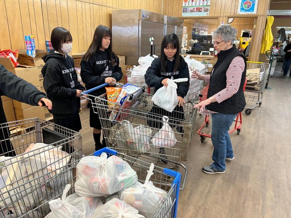 A group of Japanese high school students from Hiroshima, Japan, volunteered at the Alliance Community Pantry on Tuesday, March 28, 2023. Pictured with them is another volunteer Cathy Brogan.