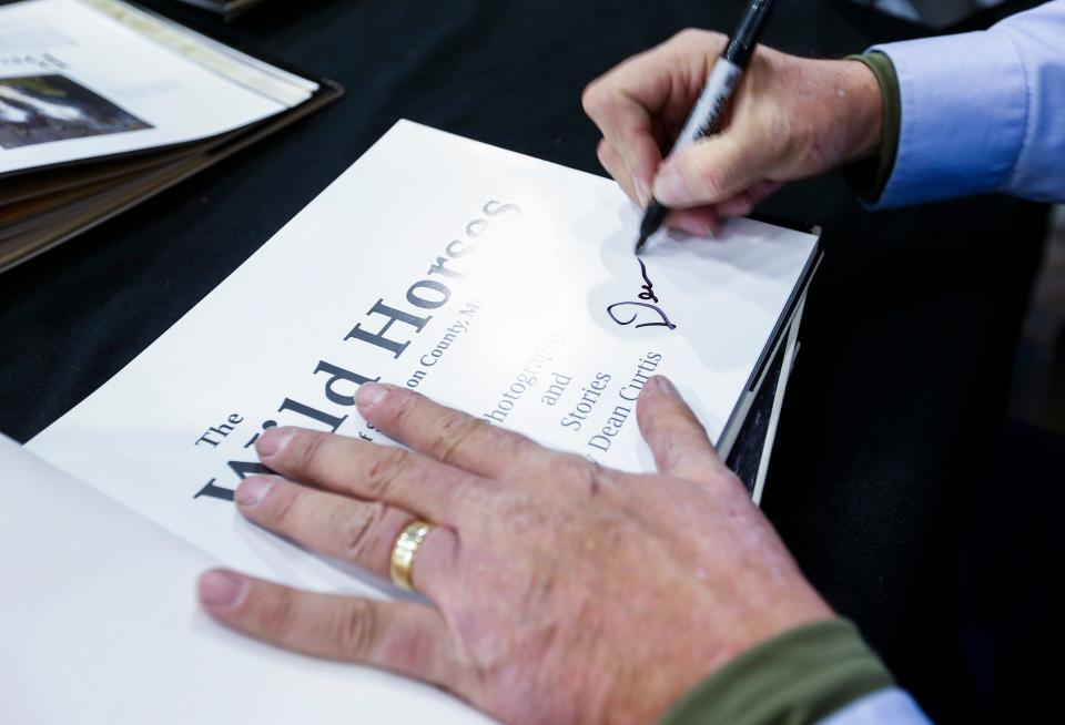 Former News-Leader photo editor Dean Curtis signs a copy of his book "The Wild Horses of Shannon County, Missouri", on Saturday, Nov. 19, 2022 at the Library Center. Curtis has been photographing the wild horses of Shannon County for over a decade and turned his photos into a 128-page coffee table book.