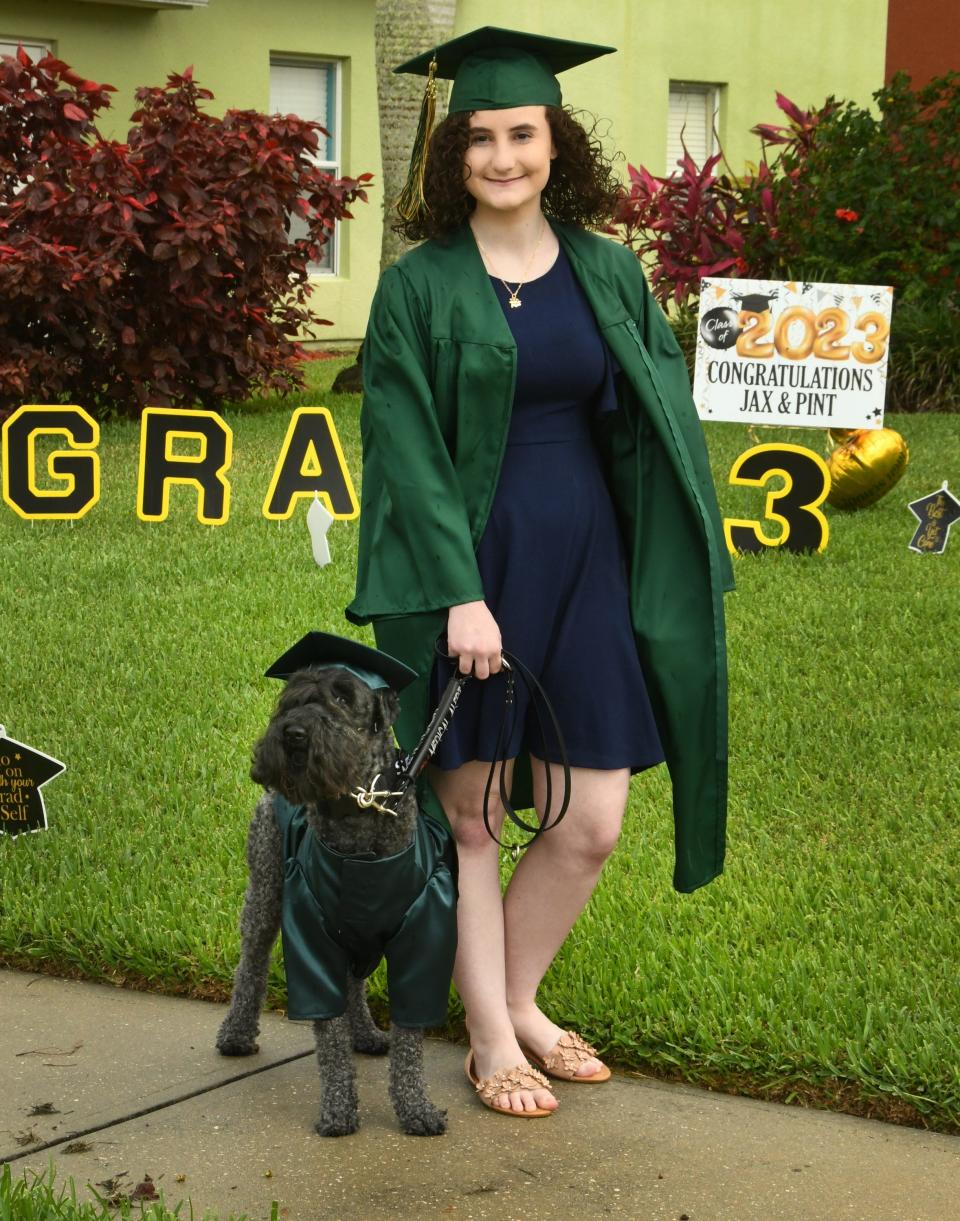 Viera High School senior Jax Russack-Cradeur, 18, stood in front of her family's house with her service dog Pint, a 5-year-old Kerry Blue Terrier, both dressed in matching caps and gowns for graduation. Russack-Cradeur, who has postural orthostatic tachycardia syndrome, graduated from Viera High School Friday with Pint at her side.