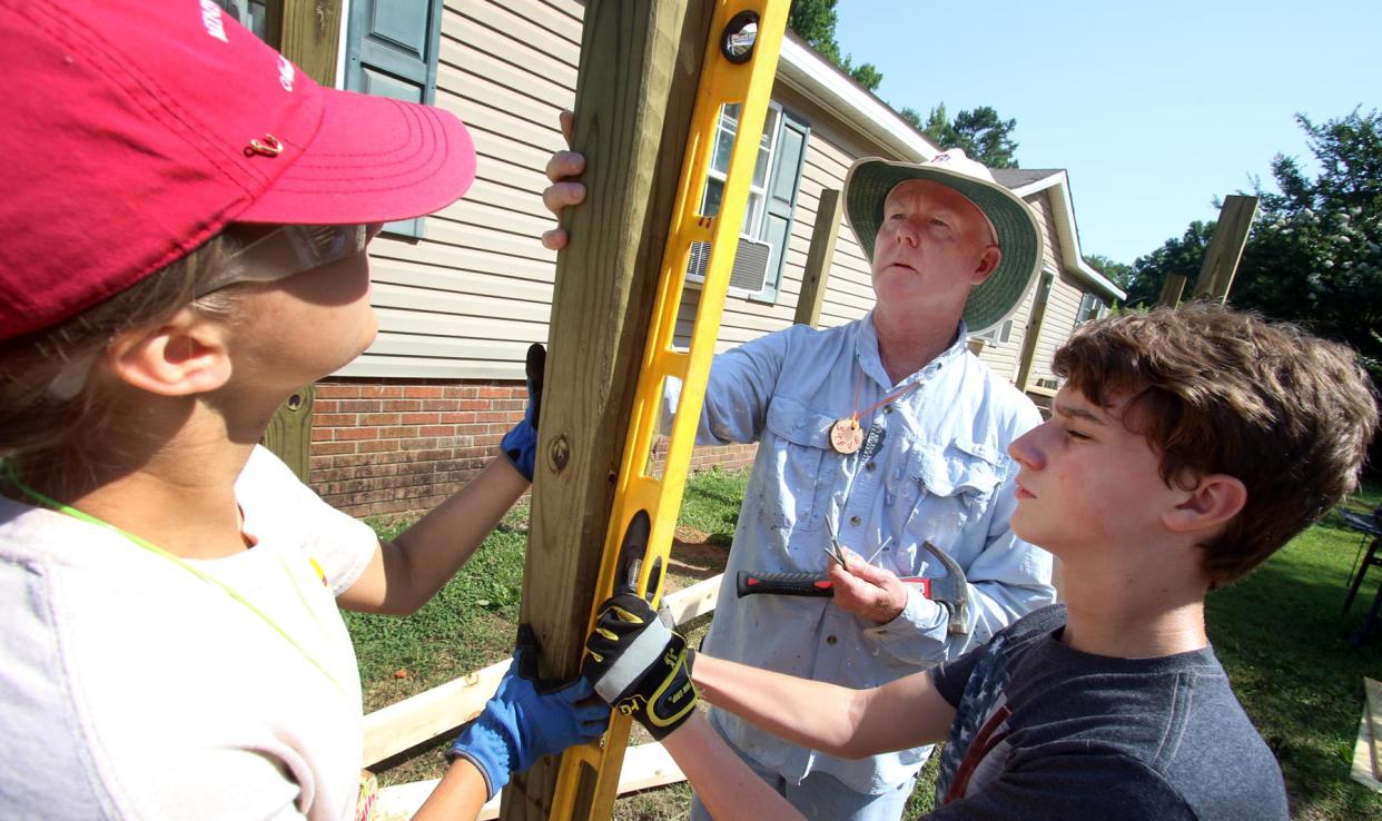Sixteen-year-old Faith Nyberg, Steve Barfield and 13-year-old Carson Hollingworth work to construct an entryway ramp for the Mayne family on Ellis Road Wednesday morning, June 20, 2018. Steve Barfield and a group of teen with Carolina Cross Connection in Gaston County help homeowners in need of repairs and upgrades each summer. The Glenn Foundation awarded Carolina Cross Connection a grant in 2022 to help the organization continue its work.