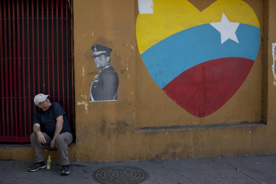 Un hombre mira hacia un afiche del fallecido presidente de Venezuela, Hugo Chávez, y a un corazón pintado con los colores de la bandera nacional del país, en Caracas, Venezuela, el martes 4 de marzo de 2014. Con motivo de la muerte de Chávez el presidente Nicolás Maduro ha decretado diez días de conmemoración que, en total, suman tres días más que el período de luto oficial concedido una semana después de su muerte. Chávez murió a los 58 años, el 5 de marzo de 2013. (AP Foto/Rodrigo Abd)