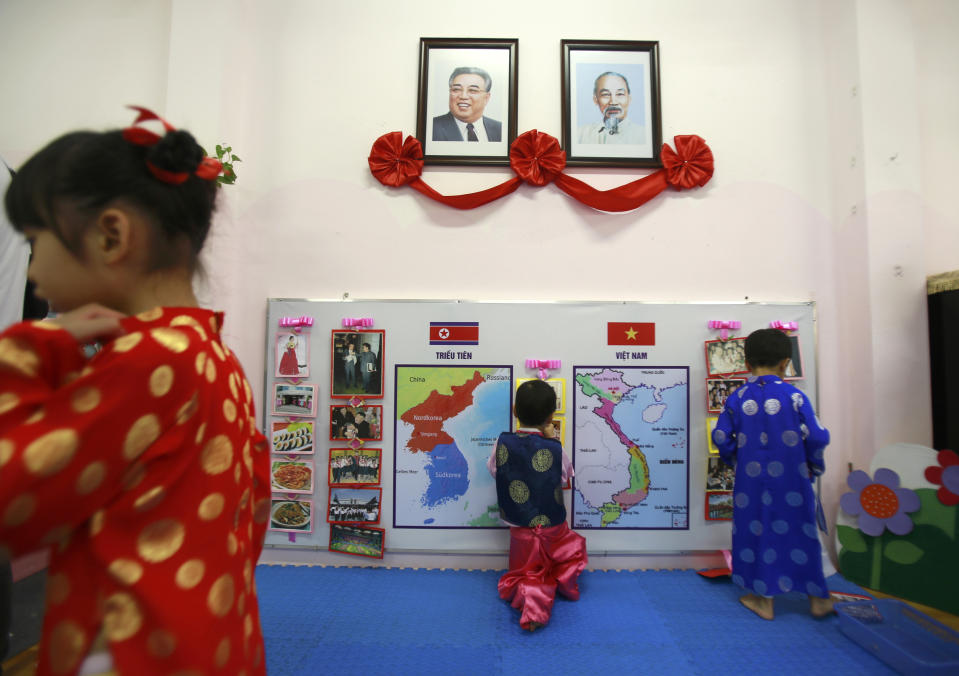 In this Thursday, Feb. 21, 2019, photo, children in Vietnamese and Korean traditional costumes stick on Vietnamese and Korean maps at Vietnam-Korea Friendship Kindergarten in Hanoi, Vietnam. Children at the kindergarten have been practicing singing and dancing, hoping to show off their talents to North Korean leader Kim Jong Un when he comes to town this week for his second summit meeting with U.S. President Donald Trump. Portraits hang on a wall are the late North Korean leader Kim Il Sung, left, and the late Vietnamese revolutionary leader Ho Chi Minh. (AP Photo/Hau Dinh)