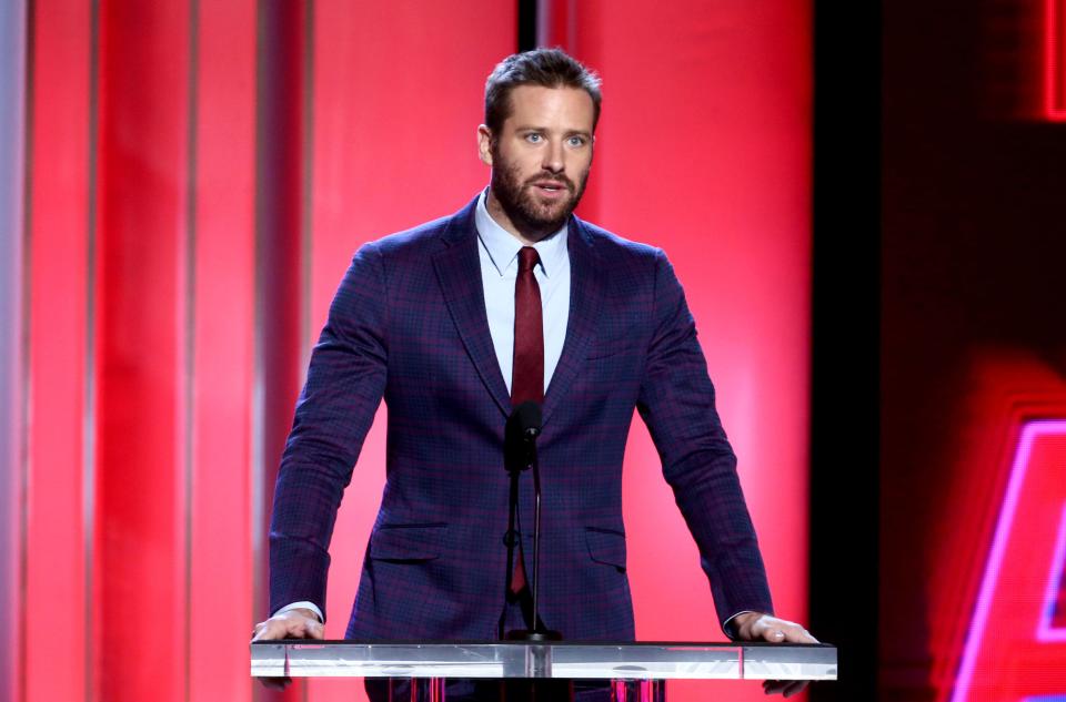 Armie Hammer looks stylish in this dark blue suit with a red tie to match