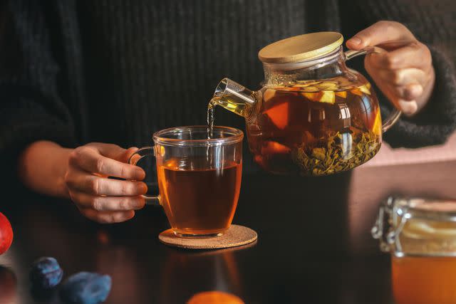 <p>Tatiana Lavrova / Getty Images</p> Female hand pouring tea into transparent cup.