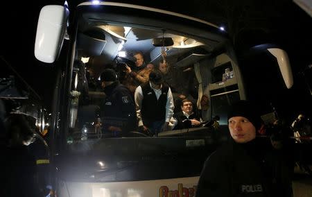 A police officer stands in front of a bus with refugees that arrived from the Bavarian town of Landshut to the Chancellery building in Berlin, Germany, January 14, 2016. REUTERS/Fabrizio Bensch