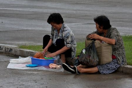 A street vendor checks her produce on a street as another woman looks on in Pyongyang, North Korea, in this picture taken September 5, 2010. REUTERS/Roman Harak/Handout via Reuters