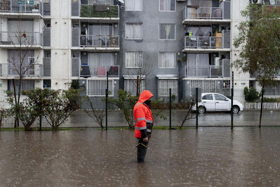 A municipal worker works on a flooded street after heavy rains in Santiago, Chile, Thursday, June 13, 2024. (AP Photo/Matias Basualdo)