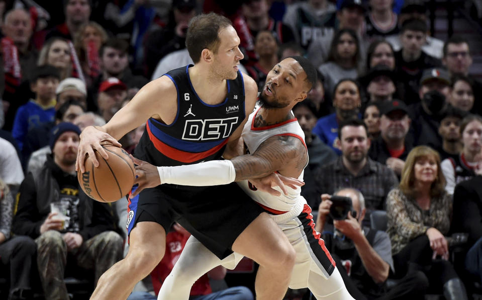 Portland Trail Blazers guard Damian Lillard, right, reaches in to try and poke the ball away from Detroit Pistons forward Bojan Bogdanovic during the first half of an NBA basketball game in Portland, Ore., Monday, Jan. 2, 2023. (AP Photo/Steve Dykes)