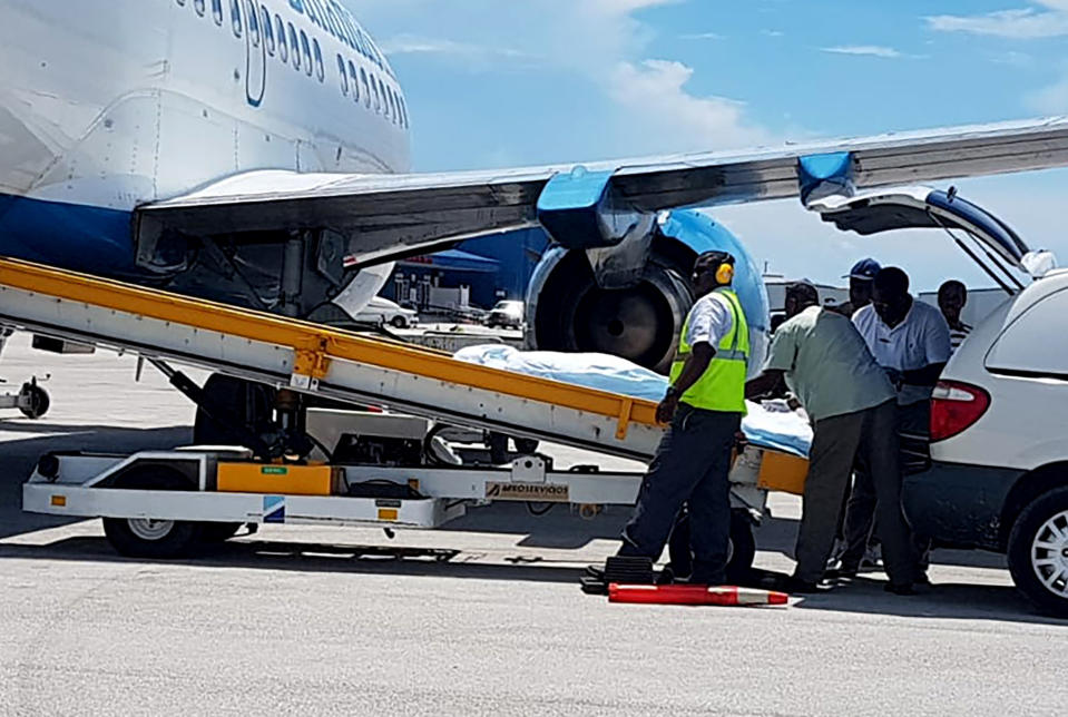 In this handout photo released by the Bahamas ZNS Network, employees oversee the arrival of the bodies of four women and three men, including billionaire coal entrepreneur Chris Cline and his daughter, at the airport in Nassau, Bahamas, Friday, July 5, 2019. The attorney’s office representing the West Virginia billionaire confirmed that he was killed in the helicopter crash along with his daughter and five other U.S. citizens. (Bahamas ZNS Network via AP)