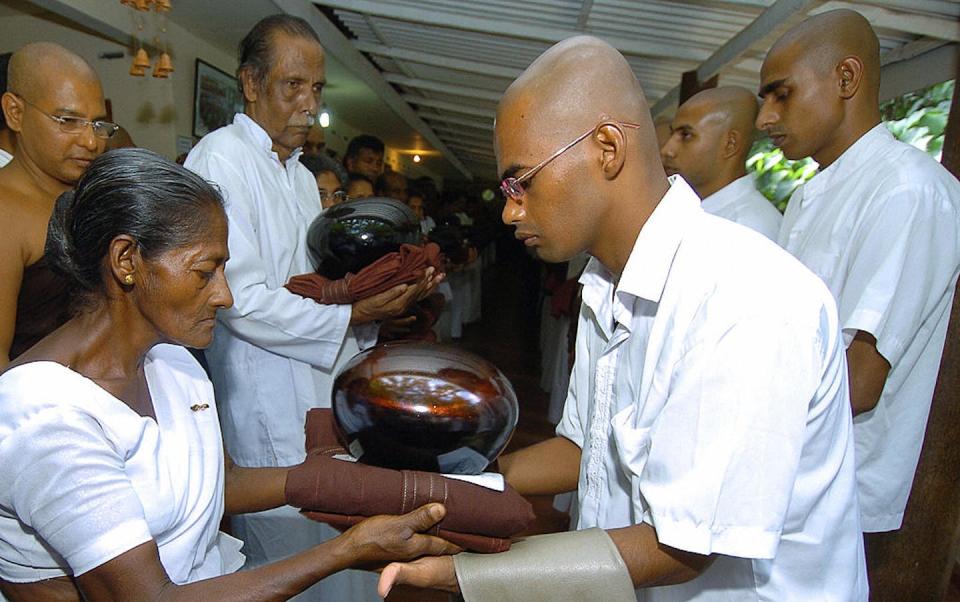 A Sri Lankan mother hands over a begging bowl and robes to her son during a ceremony, granting him permission to enter priesthood. <a href="https://www.gettyimages.com/detail/news-photo/polgahawela-sri-lanka-sri-lankan-mother-w-b-gnanawathi-news-photo/57559915?adppopup=true" rel="nofollow noopener" target="_blank" data-ylk="slk:Lakruwan Wanniarachchi/AFP via Getty Images;elm:context_link;itc:0;sec:content-canvas" class="link ">Lakruwan Wanniarachchi/AFP via Getty Images</a>