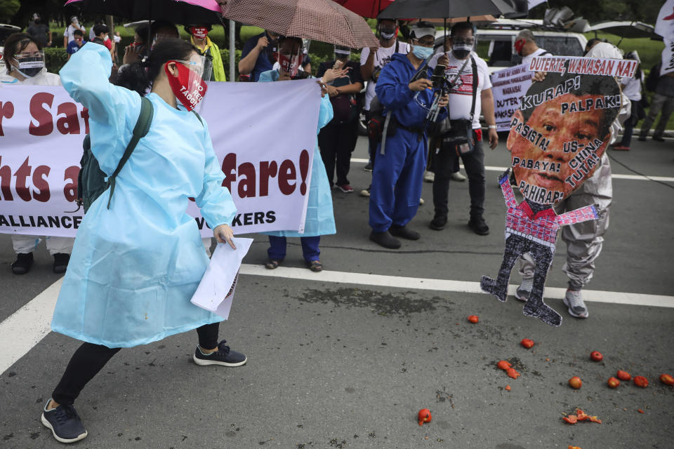 A protester hurls a tomato on a picture of Philippine President Rodrigo Duterte before marching towards the House of Representative where he is set to deliver his final State of the Nation Address in Quezon city, Philippines on Monday, July 26, 2021. Duterte is winding down his six-year term amid a raging pandemic and a battered economy. (AP Photo/Gerard Carreon)