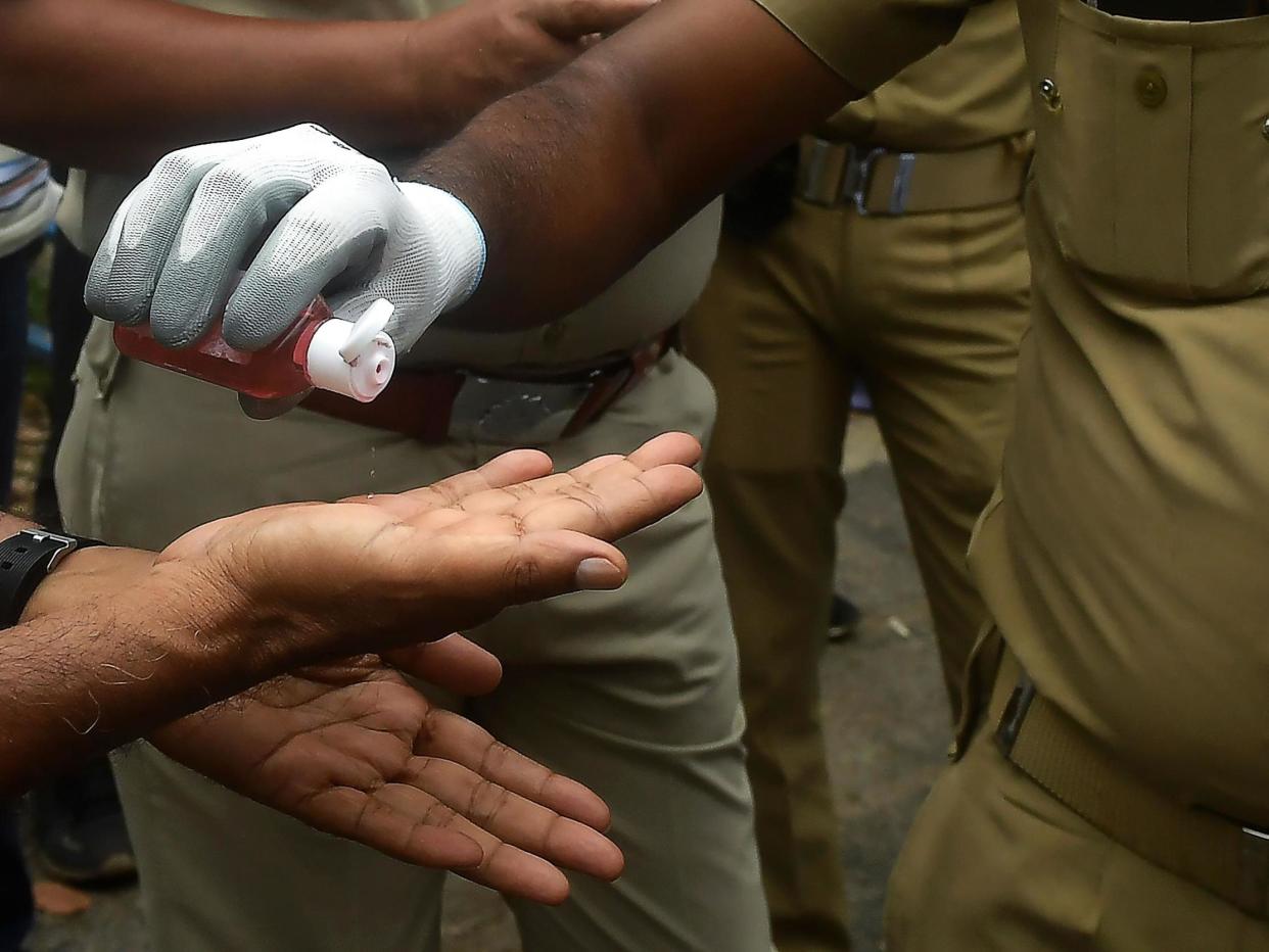 Police officers use hand sanitiser in Kolkata, India, on 27 July, 2020: Dibyangshu SARKAR / AFP via Getty Images