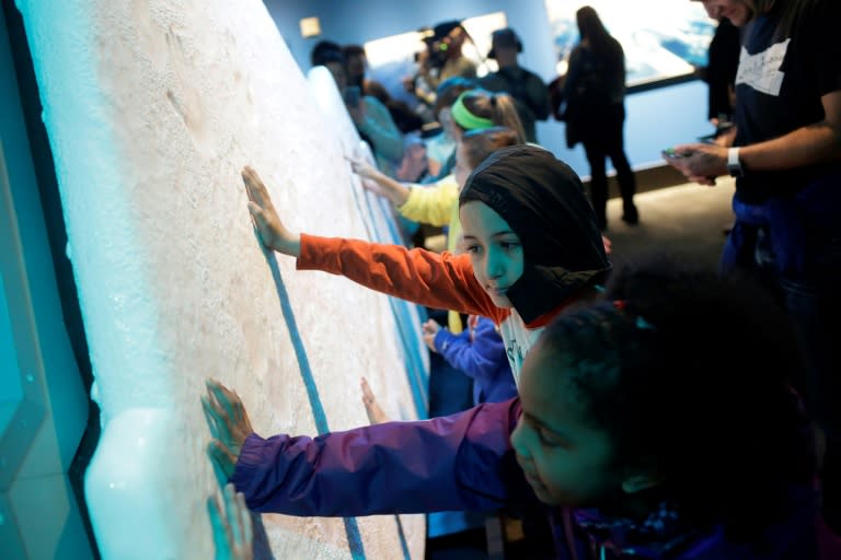 Students on a field trip place their hands on a ice glacier replica during the "Extreme Ice" exhibit at the Museum of Science and Industry in Chicago, Illinois