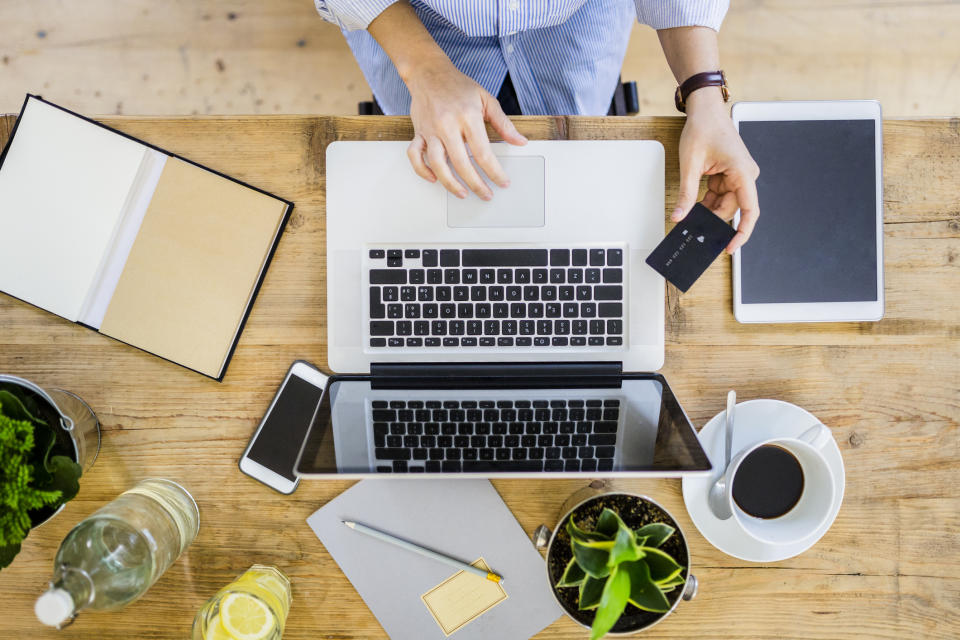 Top view of woman at wooden desk with credit card and laptop. (PHOTO: Getty Images)