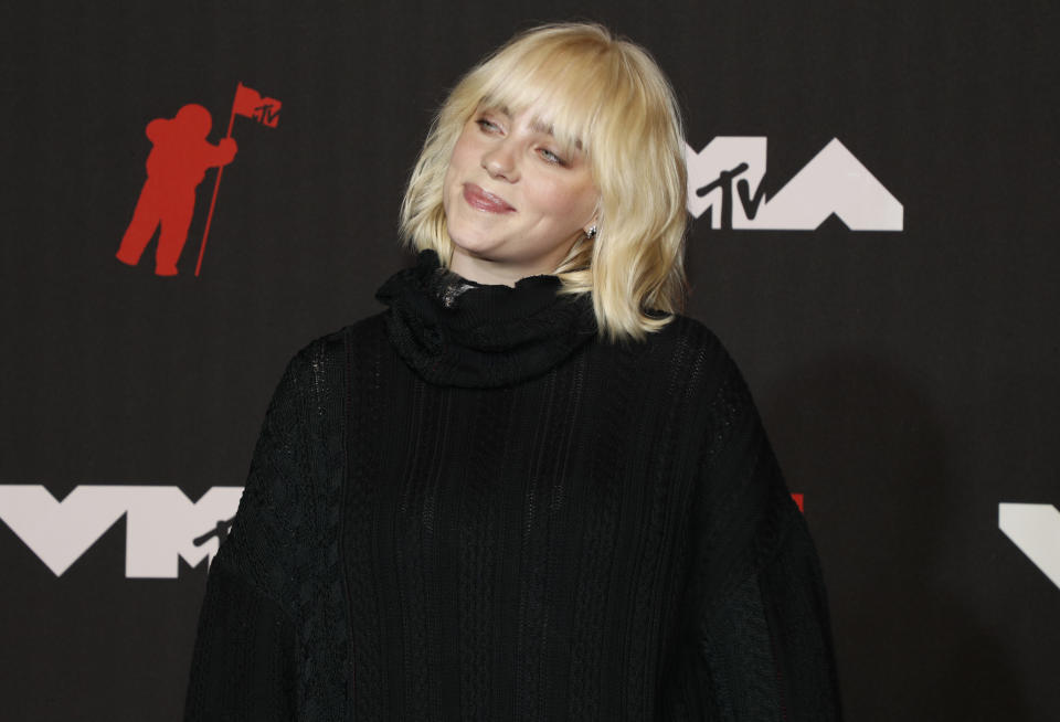 Eilish smiles with her head tilted on the red carpet