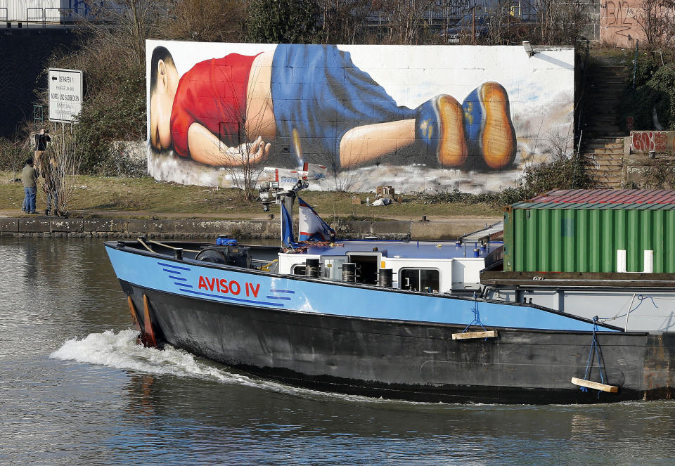 FILE - In this Thursday, March 10, 2016 file photo, graffiti depicts drowned 3-year-old refugee Aylan Kurdi on the banks of the river Main in Frankfurt, Germany. The boy was found dead in Sept. 2015 after a number of migrants died while boats carrying them to the Greek island of Kos capsized, near the Turkish resort of Bodrum. Despite the rhetoric about migration crises in Europe and the U.S., the top three countries taking in refugees are Turkey, Pakistan and Uganda. Germany comes in a distant fifth. (AP Photo/Michael Probst)