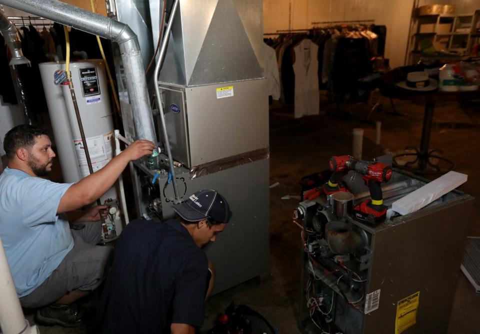 (L to R) Majestic Heating and Cooling workers Tarrick AL-Samhouri, 29 and his brother Mohammad AL-Samhouri, 23 install a new furnace and water heater in the basement of Vernon Allen of Detroit on July 1, 2021.
Both had water damage from the flooding and needed to be replaced.