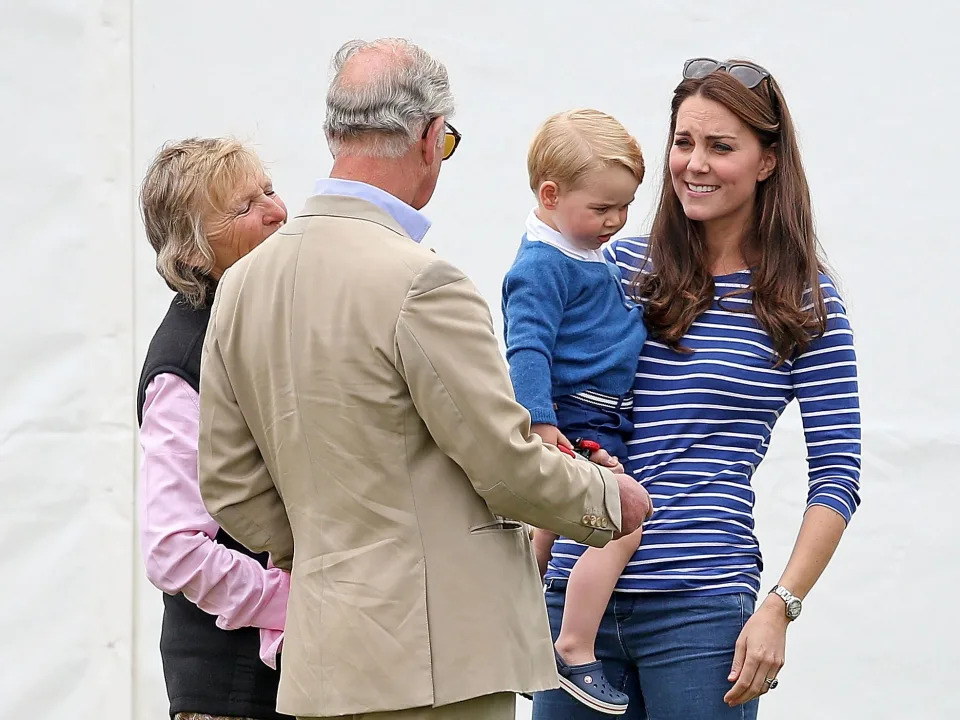 Prince Charles talks to Kate Middleton, who is holding her son Prince George
