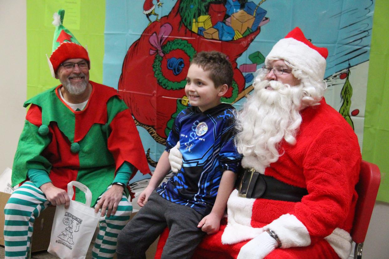 Hunter Chapin poses for a photo with Santa Claus and Papa Elf during the Community Holiday Party on Saturday, Dec. 4, 2021, at De Soto Intermediate School.