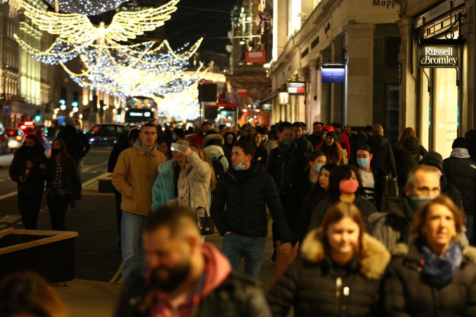 Shoppers walk under the Christmas lights on Regents Street in London on December 6, 2020. - Shoppers returned to Englands high streets this week as shops reopened following the end of a four-week coronavirus lockdown. (Photo by Hollie Adams / AFP) (Photo by HOLLIE ADAMS/AFP via Getty Images)