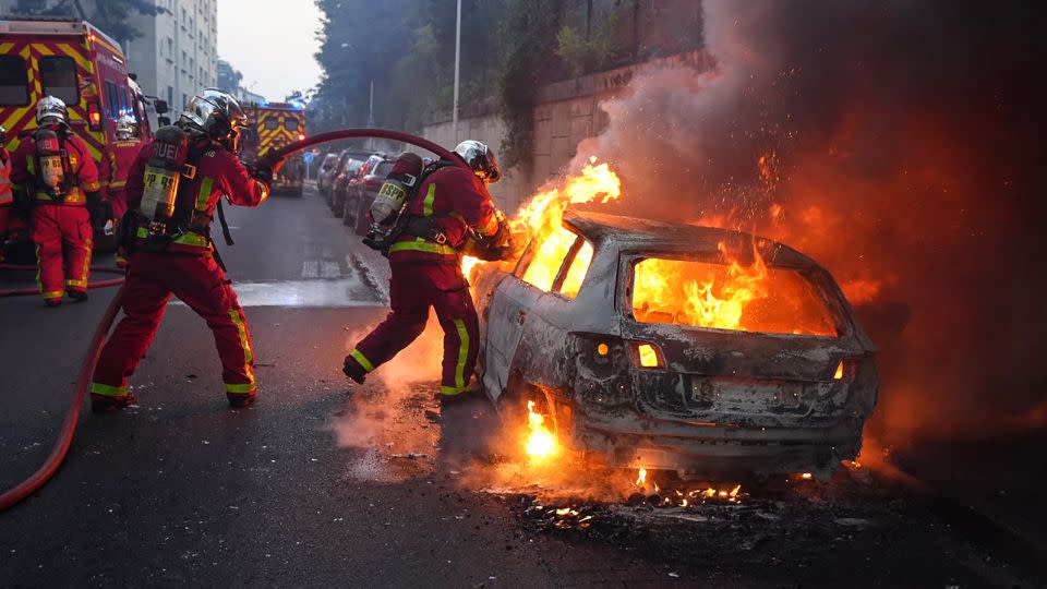 Firefighters work to put out a burning car at a protest in Nanterre, west of Paris, on June 27. - Zakaria Abdelkafi/AFP/Getty Images