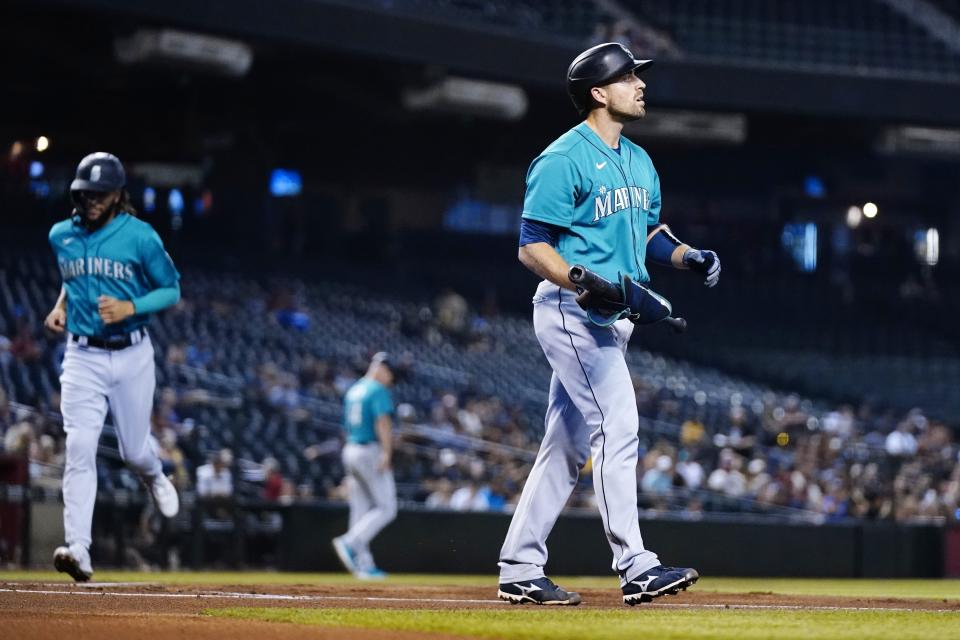 Seattle Mariners' Tom Murphy, right, pauses after earning a bases-loaded walk against the Arizona Diamondbacks as Mariners' J.P. Crawford, left, jogs home to score a run during the first inning of a baseball game Friday, Sept. 3, 2021, in Phoenix. (AP Photo/Ross D. Franklin)