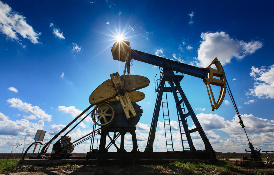 An oil pump with a bright sun and blue sky in the background.