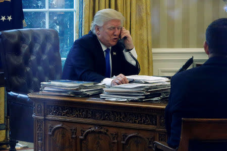 U.S. President Donald Trump speaks by phone with Germany's Chancellor Angela Merkel in the Oval Office at the White House in Washington, U.S. January 28, 2017. REUTERS/Jonathan Ernst