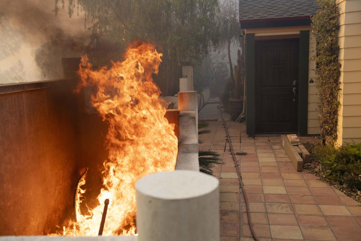 Flames burn close to an entrance of a home during the Tick Fire in Santa Clarita, Calif. on Oct. 24, 2019. The flames are fed by dry winds that are predicted to strengthen across the region.