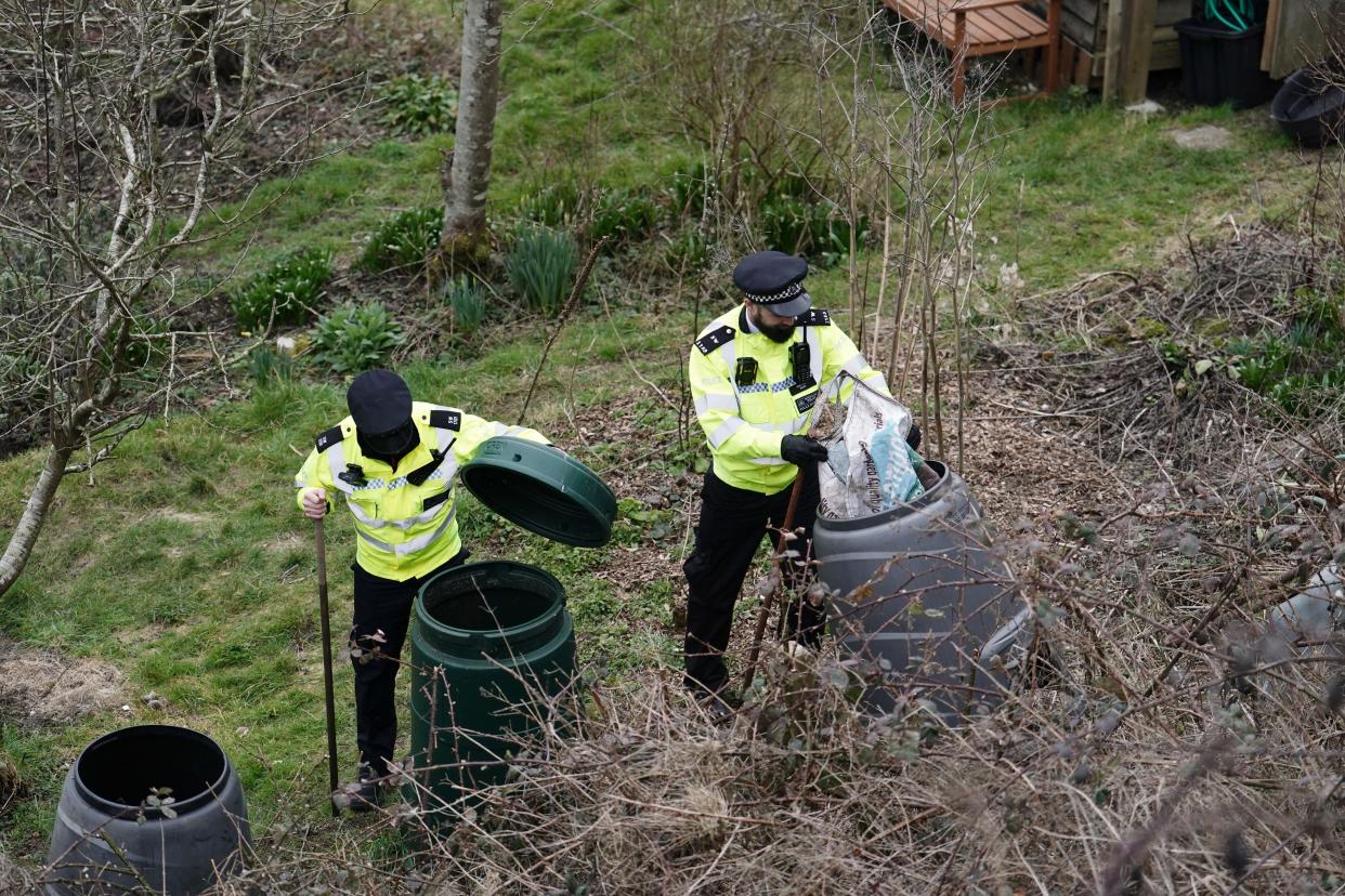 police search trash bins in wooded area