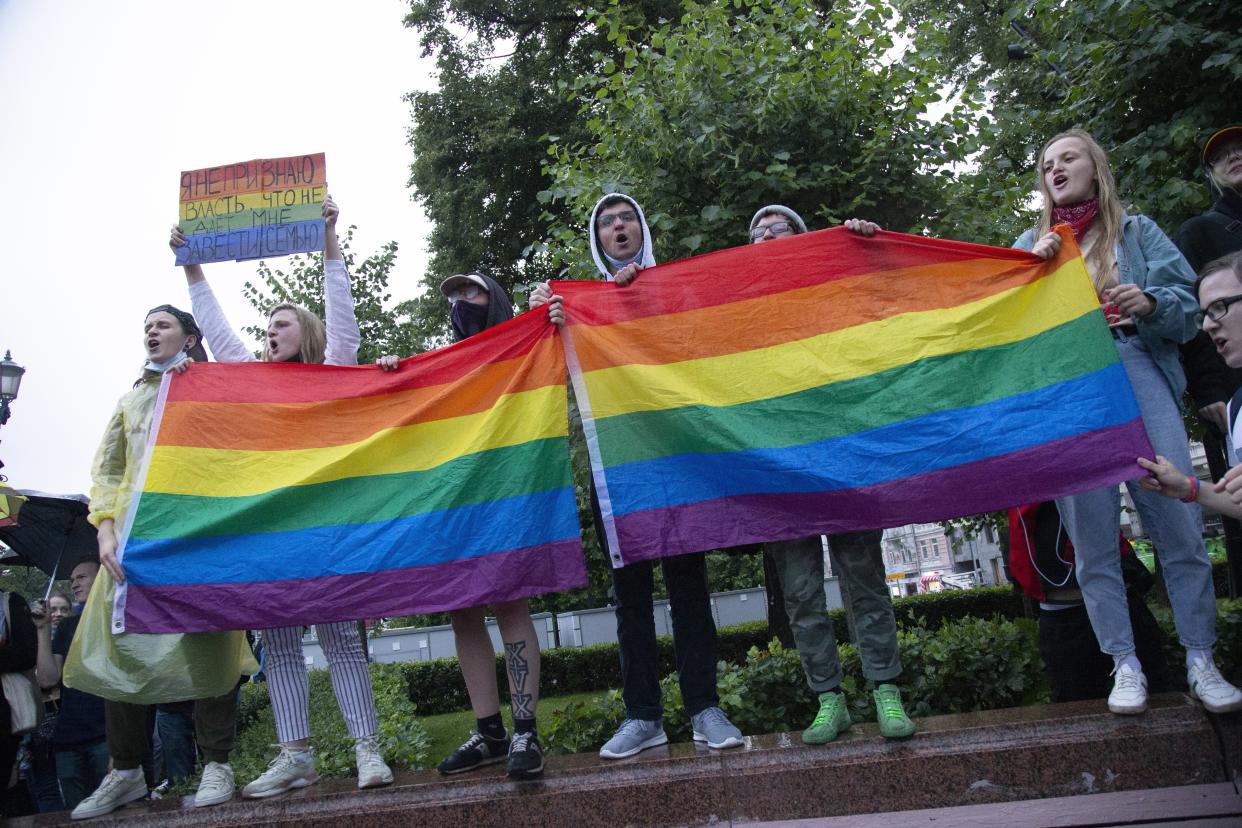 Russian LGBT activists wave rainbow-colored flags at a rally.